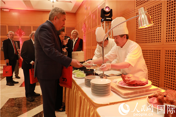 来宾们在招待会现场品尝北京烤鸭。郑琪 摄