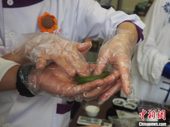 图为带教老师在“手把手”教一名留学生制作青团。　李娇阳摄