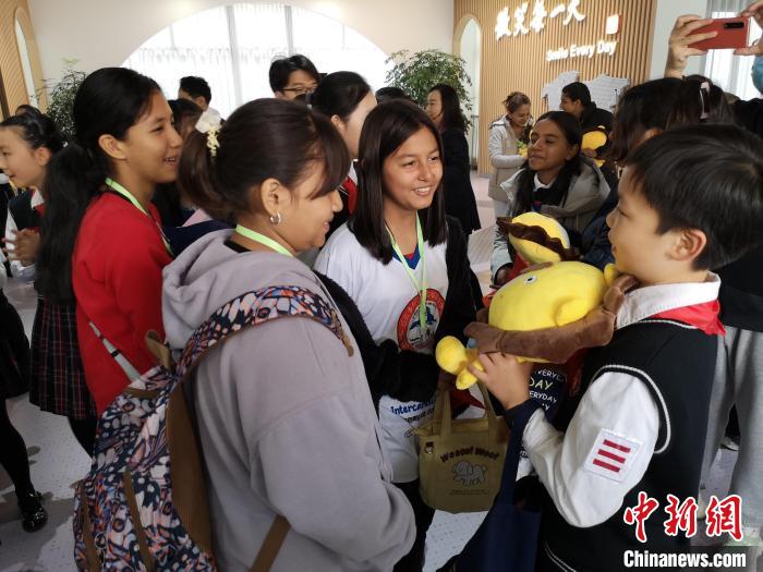 中国侨网上海市大宁国际小学学生孟刘畅（右一）给厄瓜多尔思邈维华国际学校学生送学校吉祥物。　范宇斌　摄